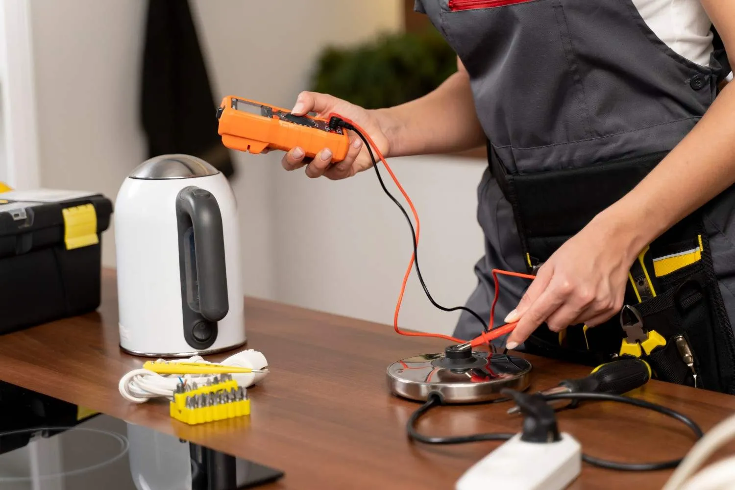 Technician testing a kitchen appliance with a multimeter