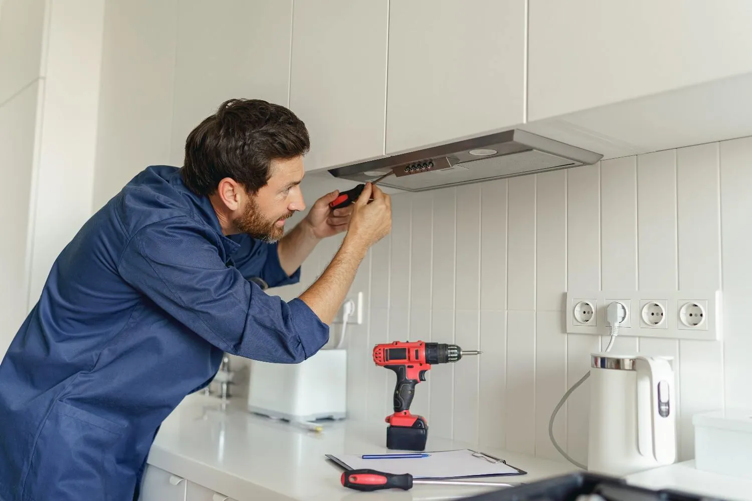 Technician testing a wall outlet in a kitchen
