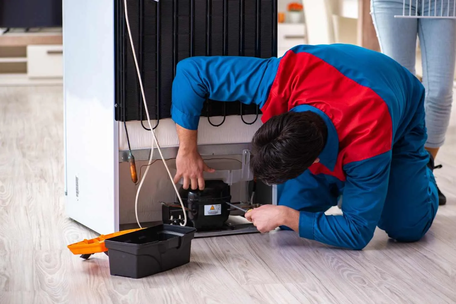 Technician repairing the back of a refrigerator