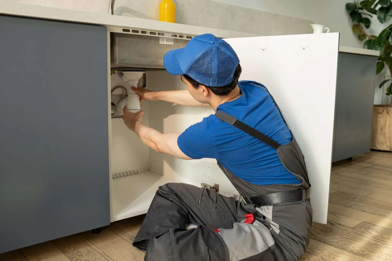 Technician fixing pipes under a sink